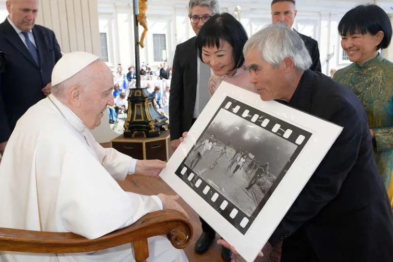 El fotógrafo Nick Ut le muestra al Papa Francisco su foto de 1972 ”El terror de la guerra”, también conocida como la ”Niña del napalm”, junto a Kim Phuc, el11 de mayo de 2022
