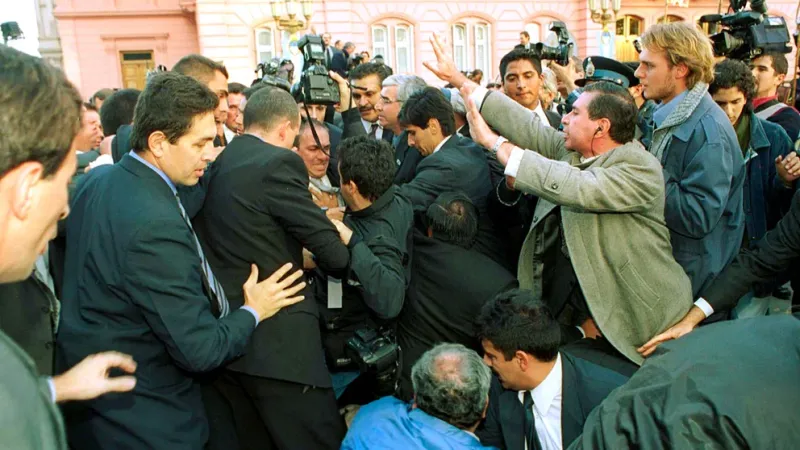 Fotógrafos y custodios forcejean para no caerse. En la foto no se ve a Kirchner: fue el momento en que el presidente se golpea con la cámara de Martín Acosta