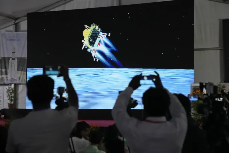 Periodistas filman la transmisión en vivo del alunizaje de la nave espacial india Chandrayaan-3 en el centro de telemetría, rastreo y comando de ISRO en Bengaluru, India (AP Foto/Aijaz Rahi)